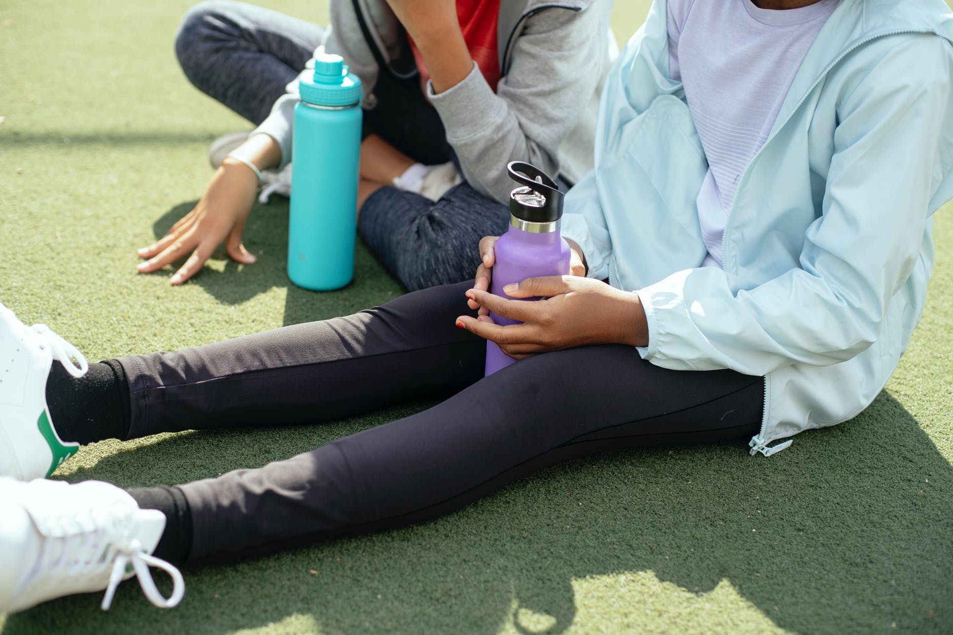 crop sportswoman with bottle on grass