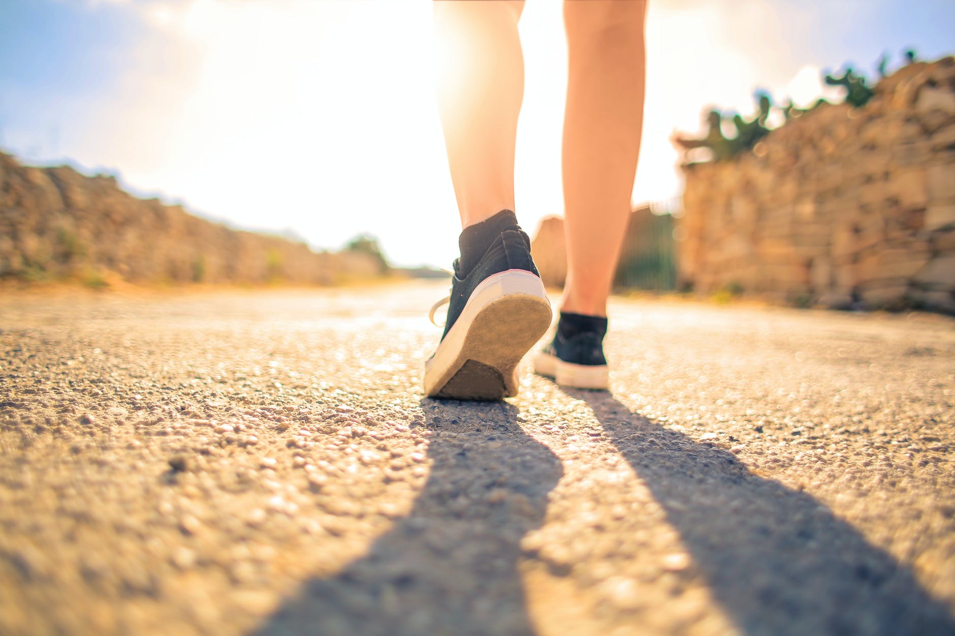 woman walking on pathway under the sun